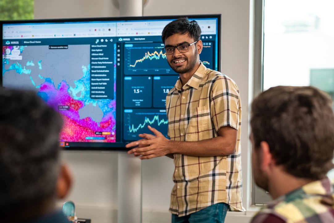 En mann står foran en stor skjerm og forteller om hva som er på den